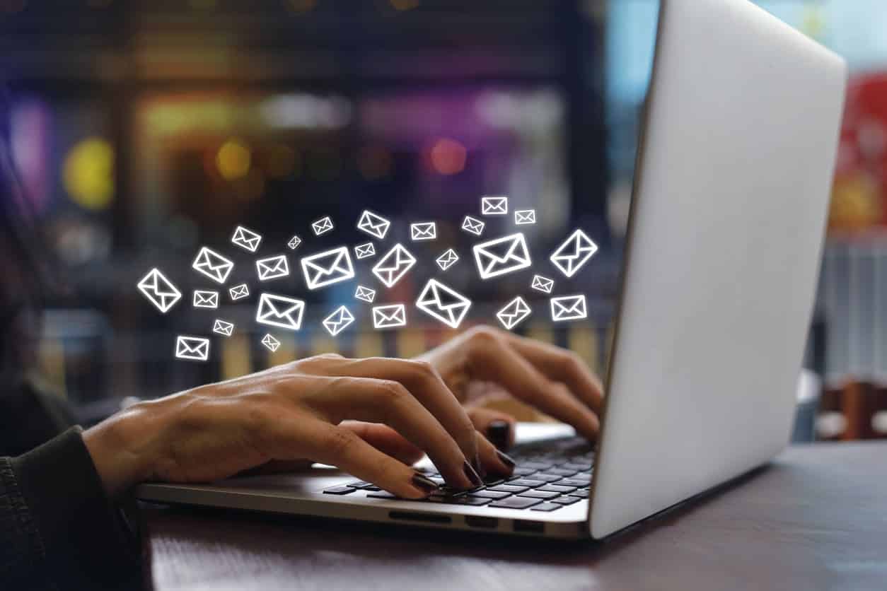 person typing on computer with email emojis