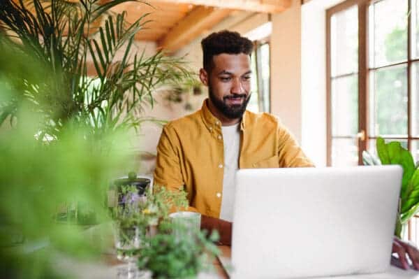 man surrounded by plants working on computer