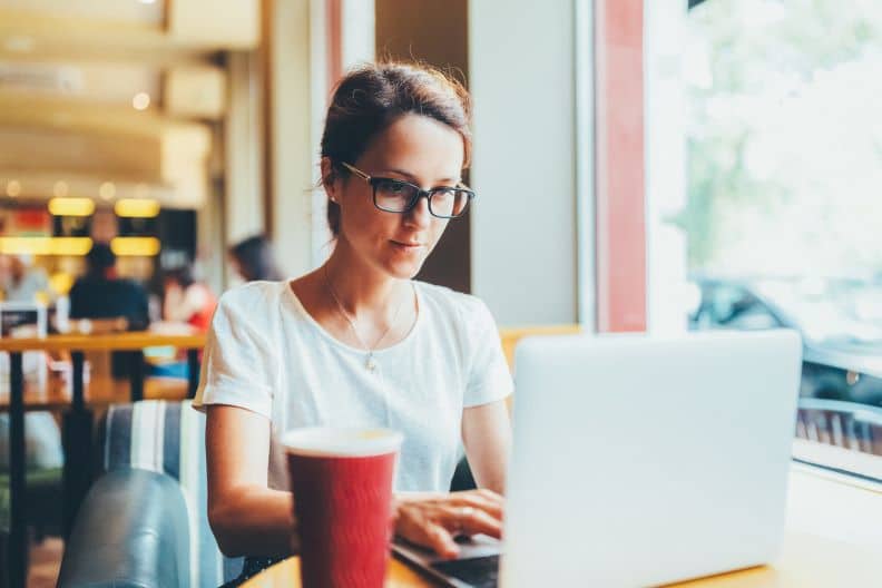 woman drafting emails in a cafe using AI Assistant